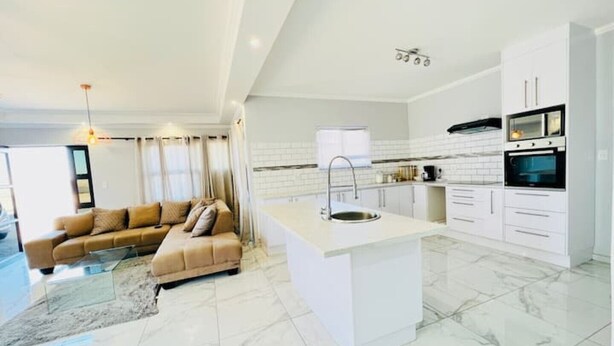 A modern kitchen with white cabinets, a central island, and a built-in oven.