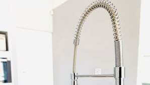 A modern kitchen sink with a chrome faucet and a flexible hose.