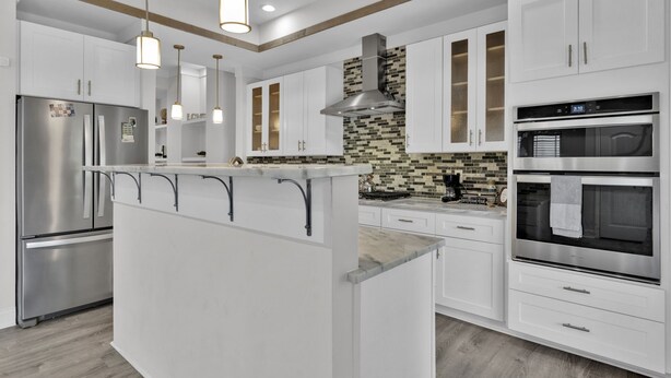 Una cocina moderna con armarios blancos, electrodomésticos de acero inoxidable y una isla central.
