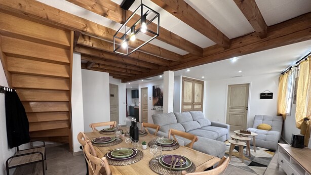 A dining area with a wooden table set for four, surrounded by wooden chairs.