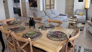 A dining area with a wooden table set for four, surrounded by wooden chairs.