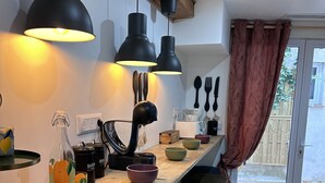 A kitchen with a wooden countertop, black bar stools, and pendant lights.