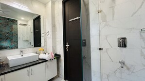 Een moderne badkamer met een witte wastafel, spiegel en een zwarte deur.