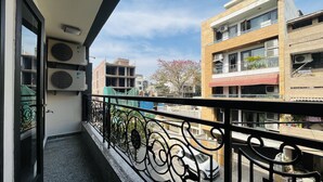 Een balkon met een metalen hekwerk, airconditioning en uitzicht op omliggende gebouwen.