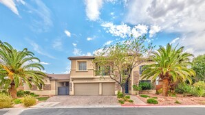 A two-story house with a garage, surrounded by palm trees and a well-maintained lawn.