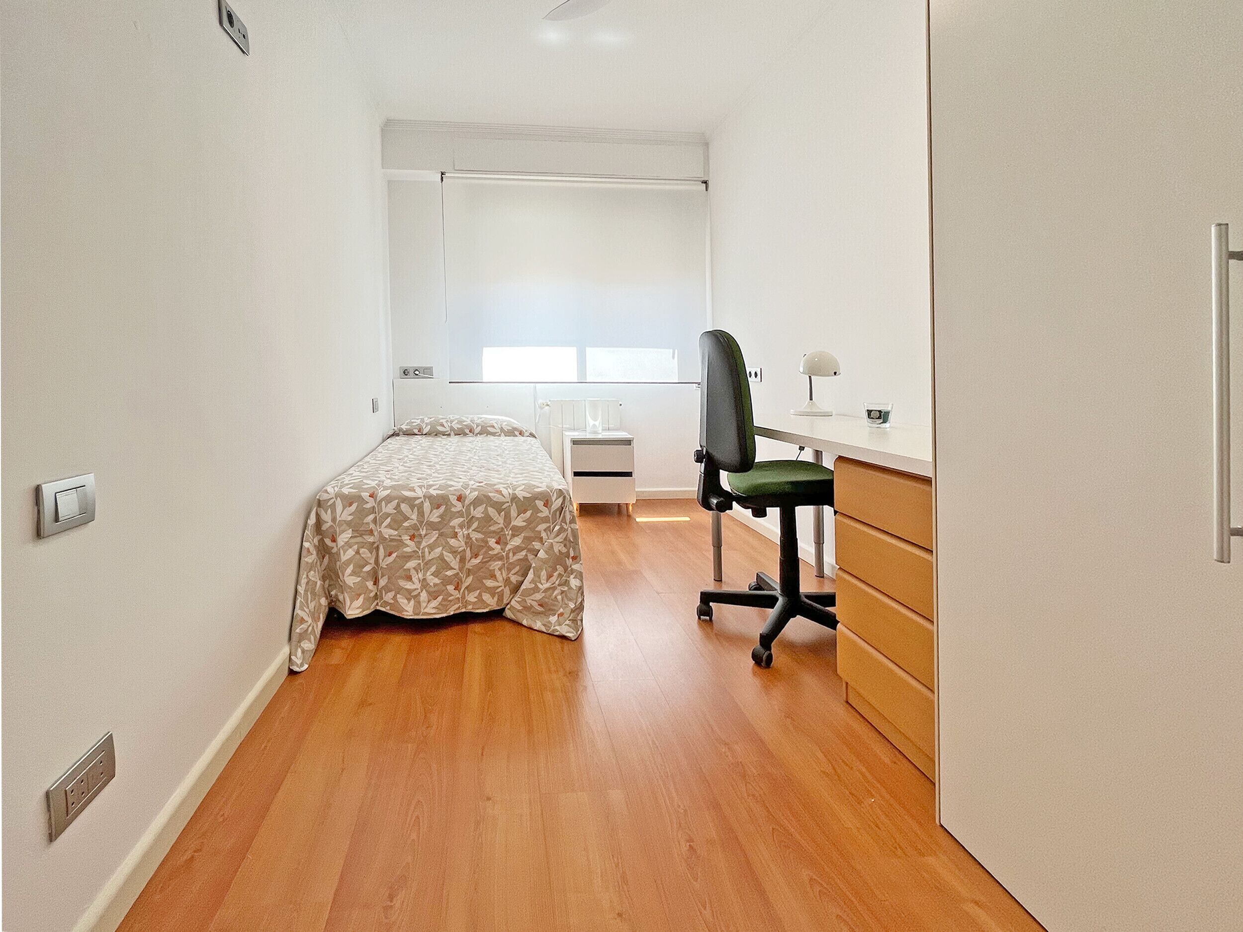 Ein Schlafzimmer mit Bett, Schreibtisch und Stuhl.