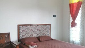 Een slaapkamer met een bed, een houten nachtkastje, een gestreept hoofdeinde en een airconditioner.