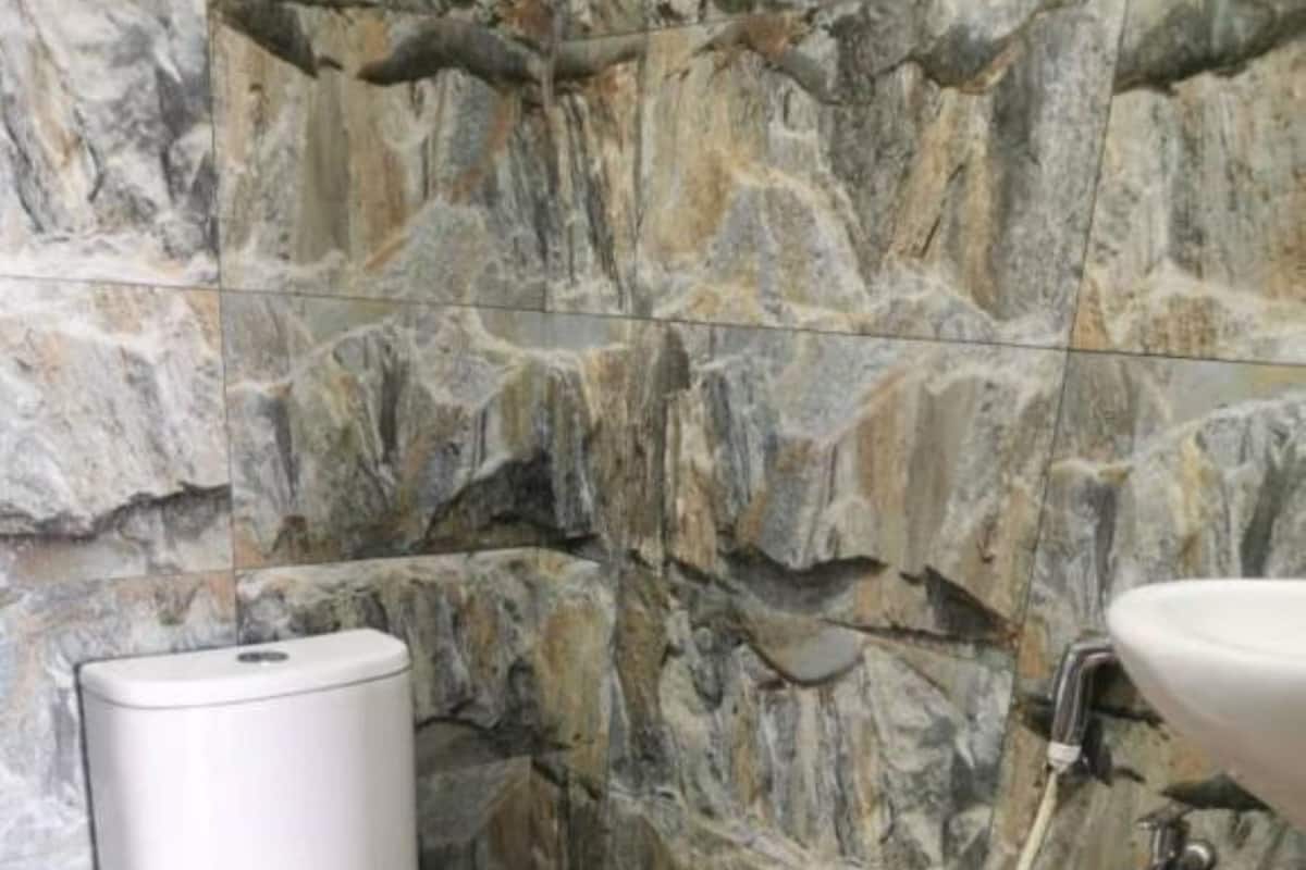 Een badkamer met een stenen muur, een toilet en een wastafel met een slang.
