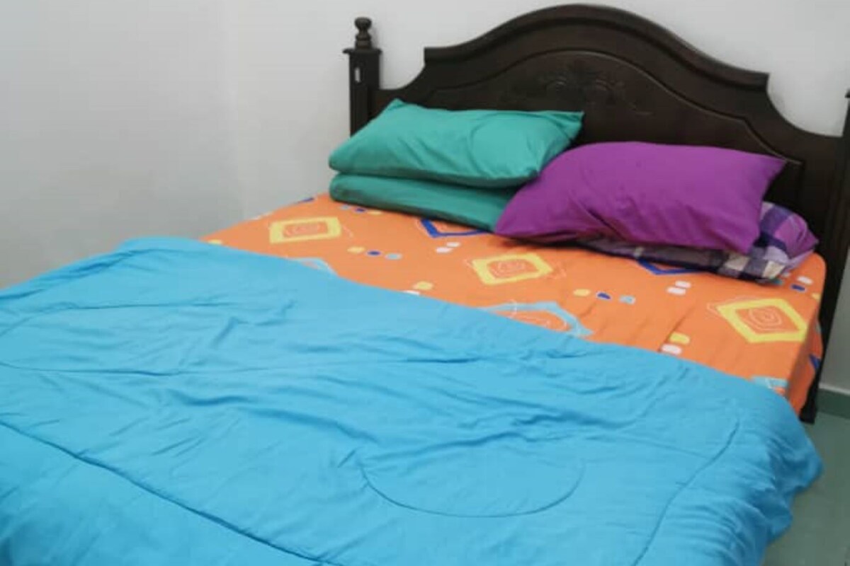 A bed with a blue bedspread and an orange patterned bedspread with pillows.