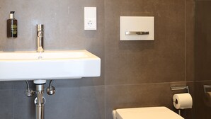 A modern bathroom with a white sink, chrome faucet, and a toilet. - Studio mit Küche 12 (München)
