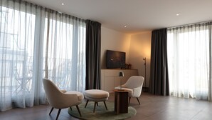 A modern living room with two armchairs, a small round table, and a television on a cabinet. - Studio mit Küche 12 (München)