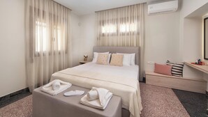 Ein Hotelzimmer mit Bett, Nachttisch, Bank und Klimaanlage.