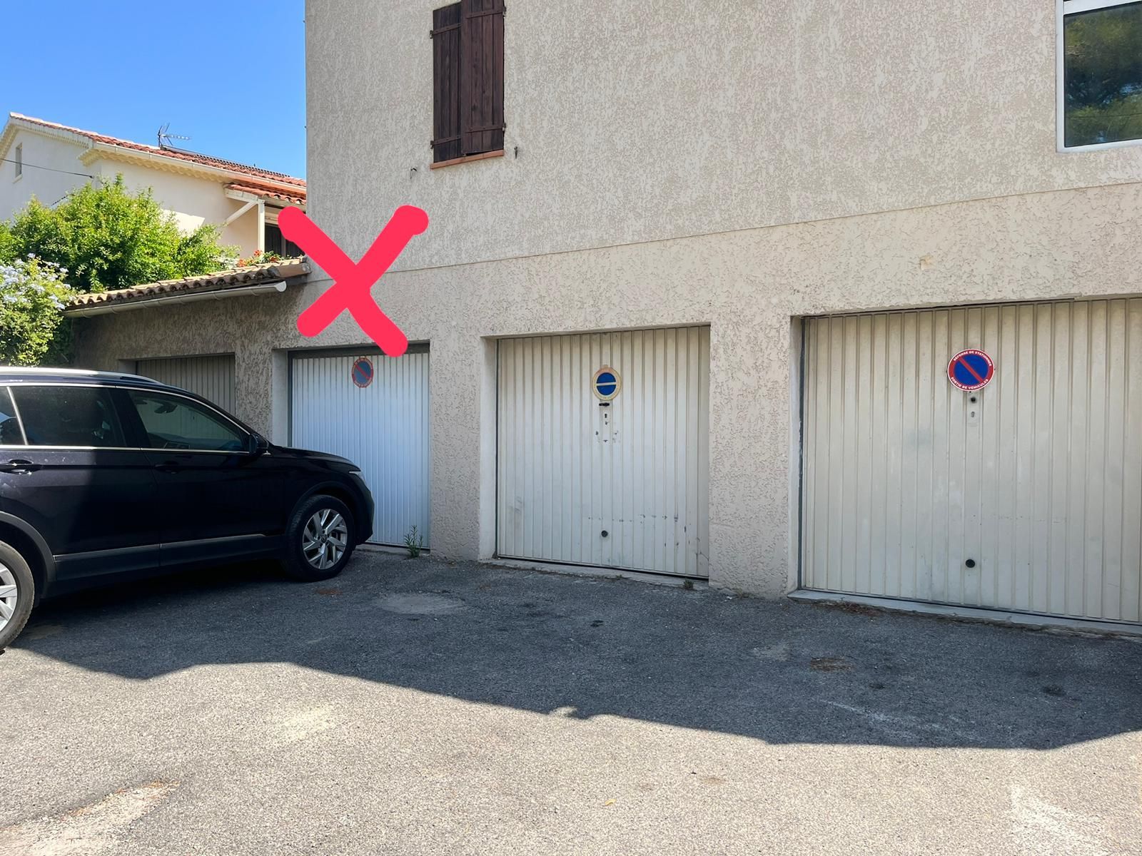 A building with three garage doors, one of which has a blue and red sign.