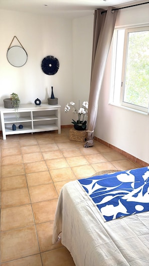 A bedroom with a bed, a white console table, a mirror, and a window with curtains.