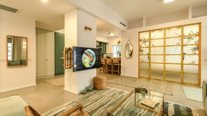 A spacious living room with a flat-screen TV, a traditional Japanese shoji screen, and a dining area with wooden furniture. - Charming 2BR Apt w a Breathtaking Patio (Tel Aviv)