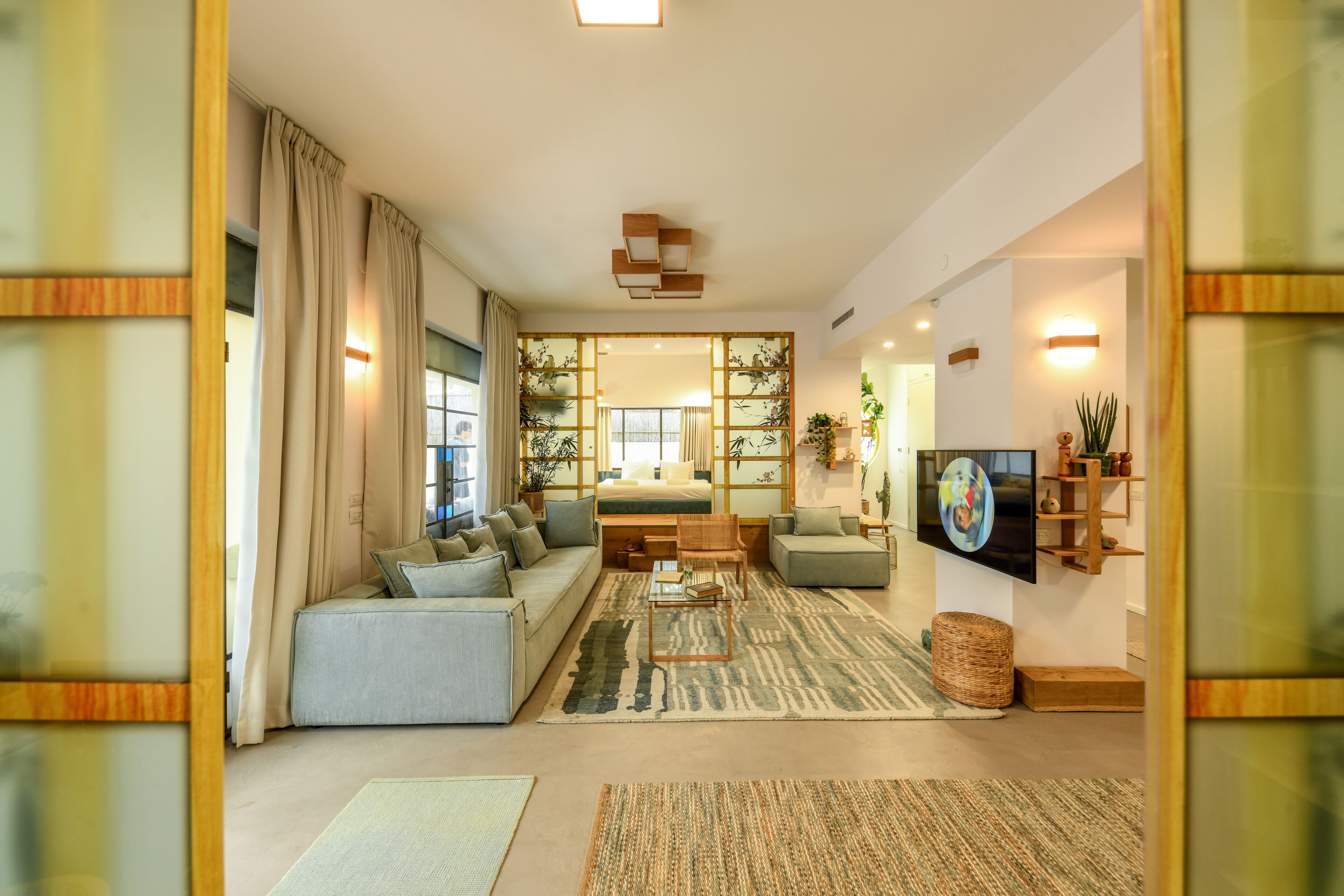 Een moderne woonkamer met een bank, fauteuils, een salontafel en een televisie.