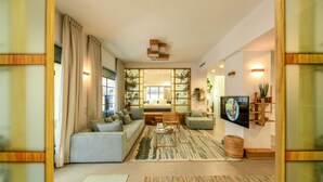 A modern living room with a sofa, armchairs, a coffee table, and a TV. - Charming 2BR Apt w a Breathtaking Patio (Tel Aviv)