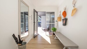 A hallway with a bench, a plant, and a wall-mounted bag rack. - Seagrass - Pet Friendly - 10 Mins Walk to Beach (Vincentia)