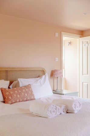 Una habitación de hotel con cama, almohadas, lámpara y puerta.