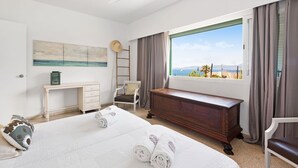 A hotel room with a bed, a desk, a dresser, a chair, and a view of the sea. - Chalet Can Contestí (Llucmajor)
