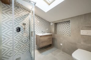 Uma casa de banho moderna com chuveiro, lavatório e sanita.