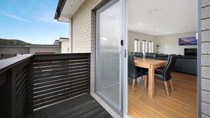 Een moderne keuken met een groot eiland, een zithoek met een houten tafel en stoelen, en een schuifdeur naar een buitenruimte.
