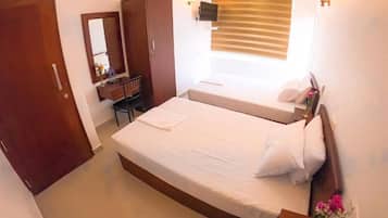 A bedroom with a large bed, a desk, a wardrobe, and a window with blinds.