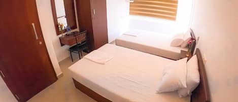 Een slaapkamer met een groot bed, een bureau, een kledingkast en een raam met jaloezieën.
