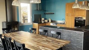Eine moderne Küche mit einem Holztisch, schwarzen Stühlen und einer integrierten Kochinsel.