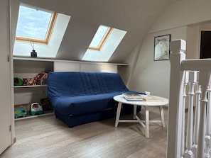 A room with a blue sofa, a small round table, and two skylights. - Villa Jersey (Saint-Germain-sur-Ay)