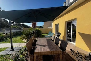 An outdoor patio with a table and chairs, a grill, and a covered area.