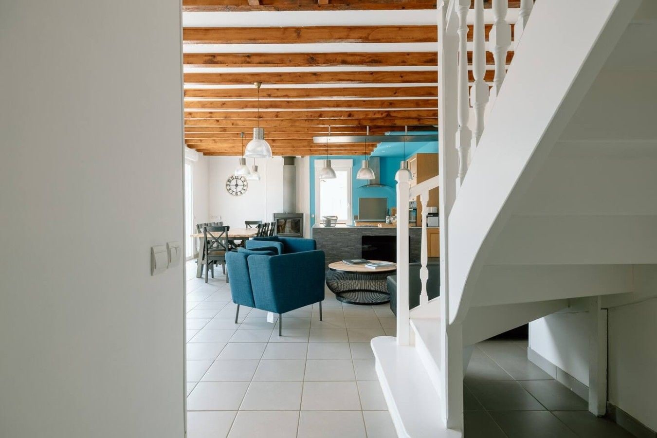A modern interior with a dining area, kitchen, and staircase.