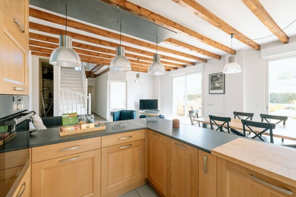 A modern kitchen with wooden cabinets, a black countertop, and pendant lighting.