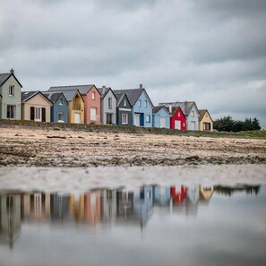 Een rij kleurrijke huizen langs een spiegelend wateroppervlak.