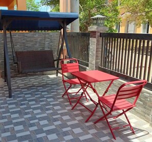 Eine Terrasse mit Tisch und Stühlen, ein überdachter Sitzbereich und eine Steinmauer.
