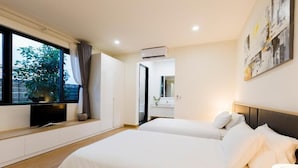 A modern hotel room with two beds, a large window, a flat-screen TV, and a bathroom visible through an open door. - SAKI VILI HO TRAM (Ho Chi Minh City)