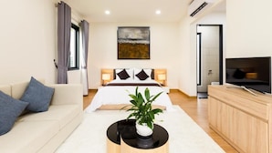 A modern hotel room with a bed, a sofa, a TV, and a plant. - SAKI VILI HO TRAM (Ho Chi Minh City)