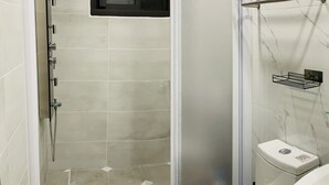 Un baño con ducha de vidrio, inodoro y lavamanos.