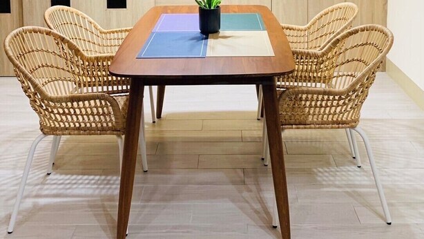 Una cocina moderna con armarios de madera, horno empotrado y comedor con mesa y sillas de mimbre.