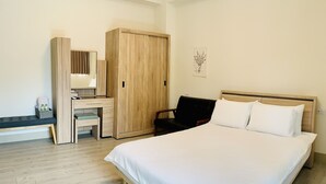 Un dormitorio con una cama grande, un armario de madera, un escritorio con silla y un banco.