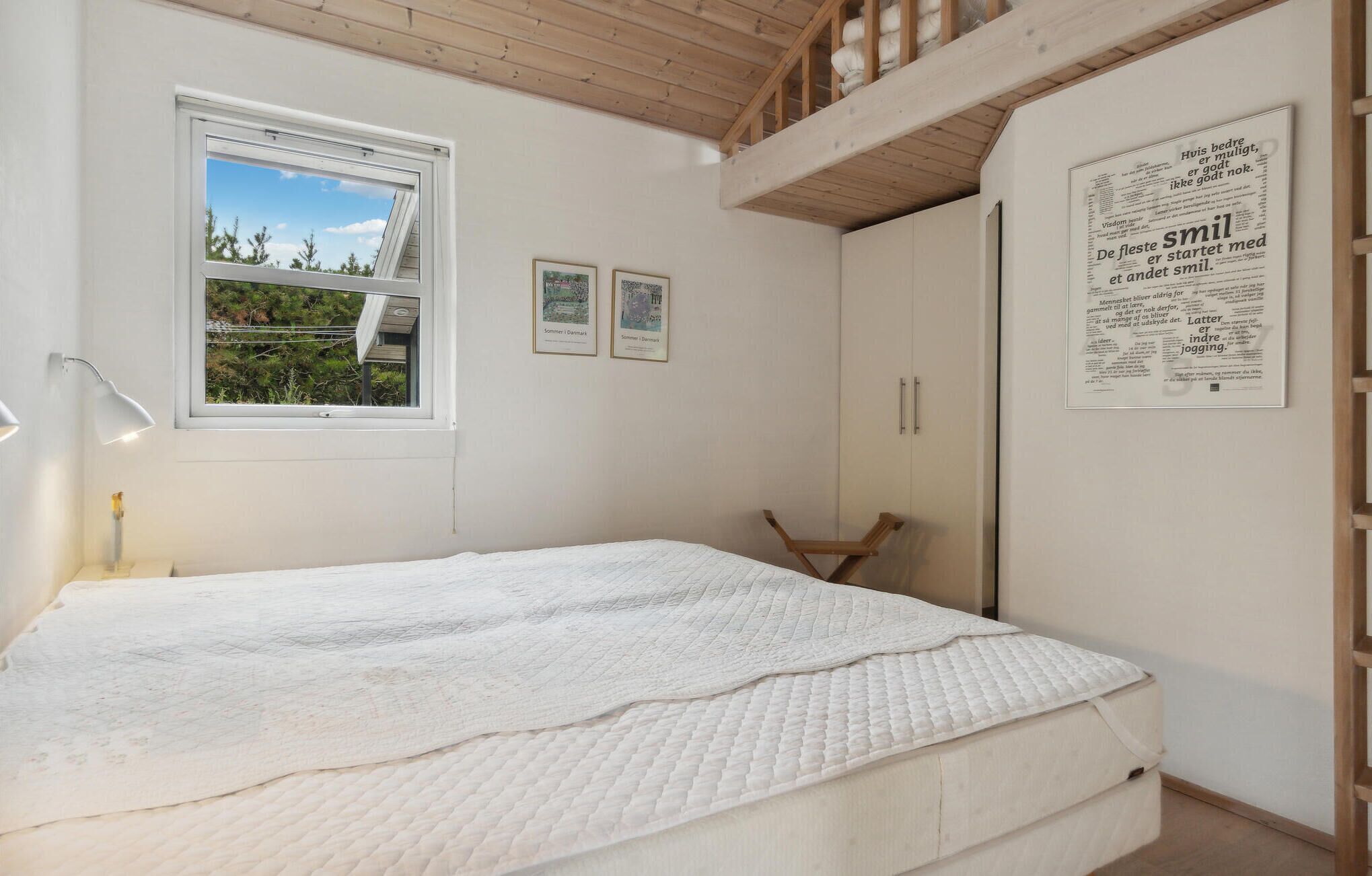 Une chambre à coucher avec un lit, une fenêtre et un mur orné de tableaux encadrés.