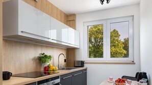Una cocina moderna con encimera de madera, un lavamanos y una ventana con vistas a árboles.