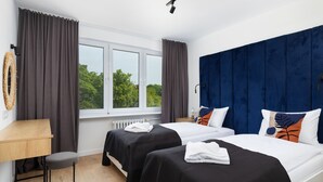 Habitación de hotel con dos camas, un escritorio y vistas a zonas verdes.
