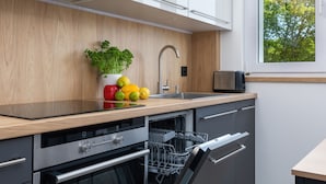 Una cocina moderna con encimera de madera, electrodomésticos de acero inoxidable y una ventana con vistas a árboles.
