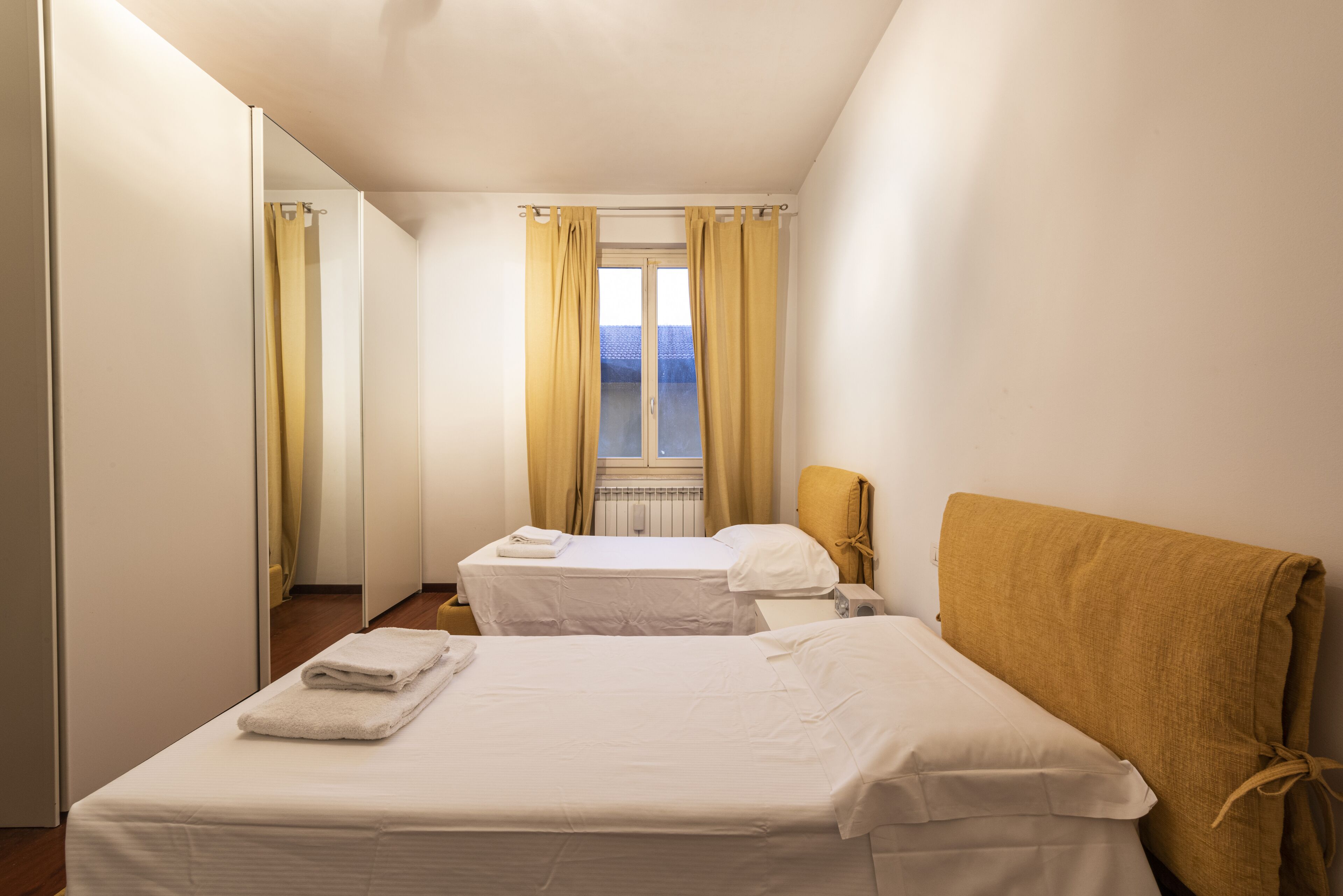 Une chambre d’hôtel avec deux lits, une fenêtre avec des rideaux et une vue sur le ciel.