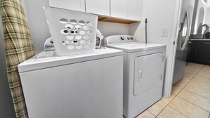 A compact laundry area with a washing machine, dryer, and a drying rack. - Private 4 BDR Oasis in Kissimmee with Pool | BBQ (Kissimmee)