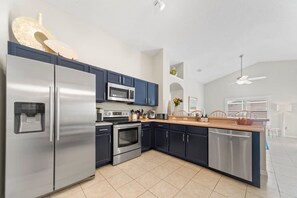 Uma cozinha moderna com eletrodomésticos de aço inoxidável, armários escuros e bancada de madeira.