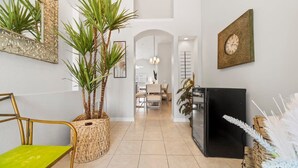 A modern interior with a dining area, a refrigerator, and decorative plants. - Private 4 BDR Oasis in Kissimmee with Pool | BBQ (Kissimmee)