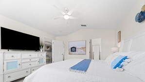 A bedroom with a bed, a television, a ceiling fan, a dresser, and a painting on the wall. - Private 4 BDR Oasis in Kissimmee with Pool | BBQ (Kissimmee)