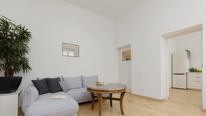 A modern living room with a grey sofa, a round wooden coffee table, and a large potted plant. - Atmospheric Apartment in the Old Town | Desk for Work (Warszawa)